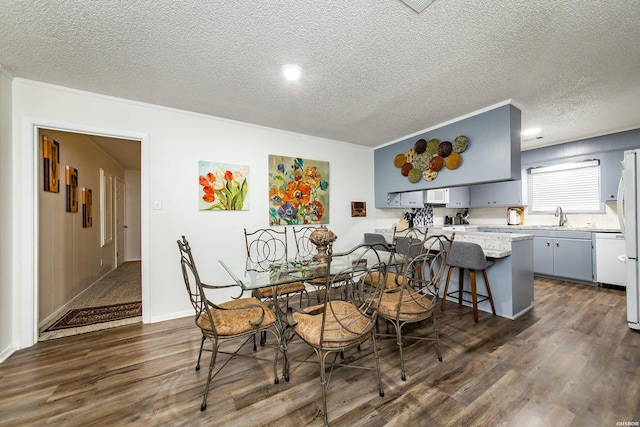 dining room with crown molding, dark wood finished floors, and a textured ceiling