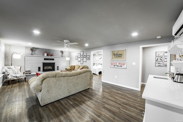 living area with a brick fireplace, dark wood-style floors, a ceiling fan, and recessed lighting