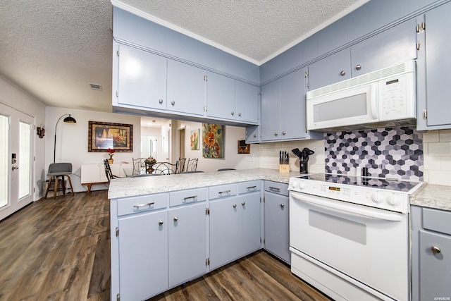 kitchen featuring a peninsula, white appliances, dark wood-type flooring, light countertops, and tasteful backsplash