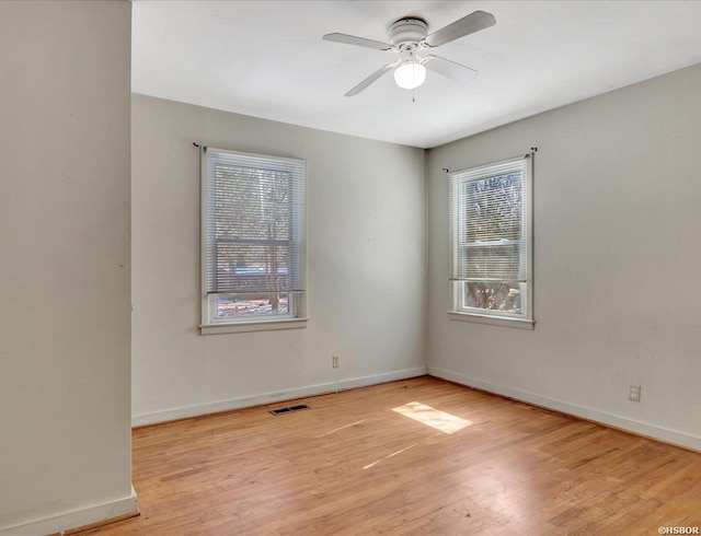 spare room featuring baseboards, visible vents, ceiling fan, and light wood finished floors