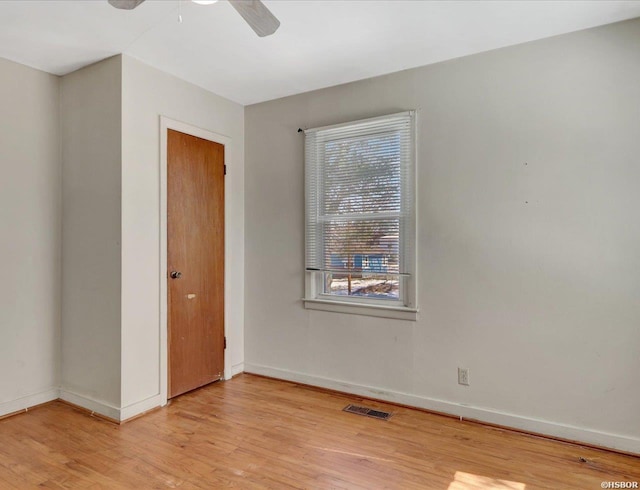 empty room with ceiling fan, light wood finished floors, visible vents, and baseboards