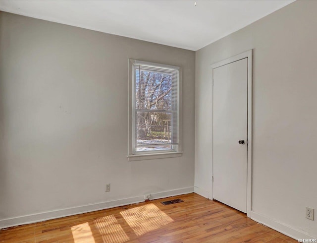 empty room featuring baseboards, visible vents, and light wood-style floors