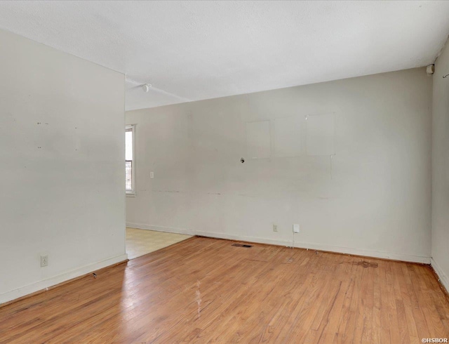 empty room featuring baseboards and light wood finished floors