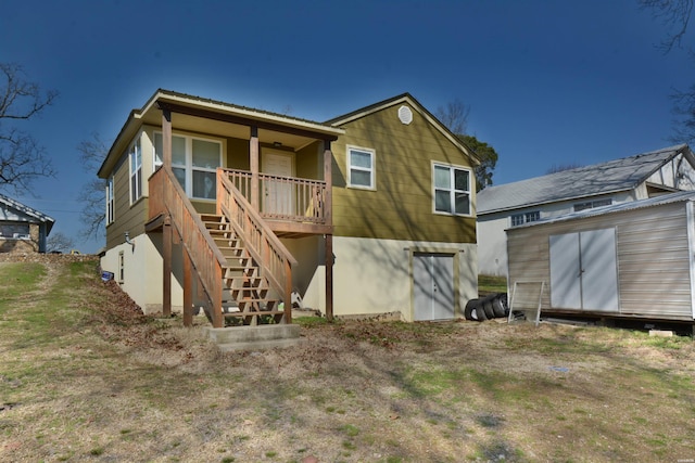 rear view of property featuring stairway, a storage unit, and an outdoor structure