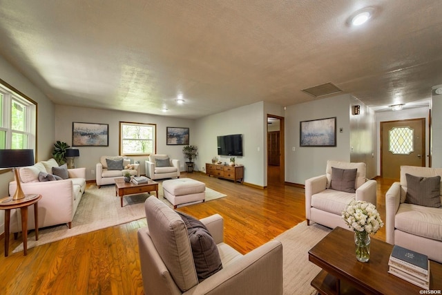 living room featuring baseboards, wood finished floors, and visible vents
