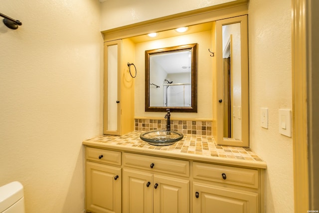 bathroom with vanity, toilet, and tasteful backsplash
