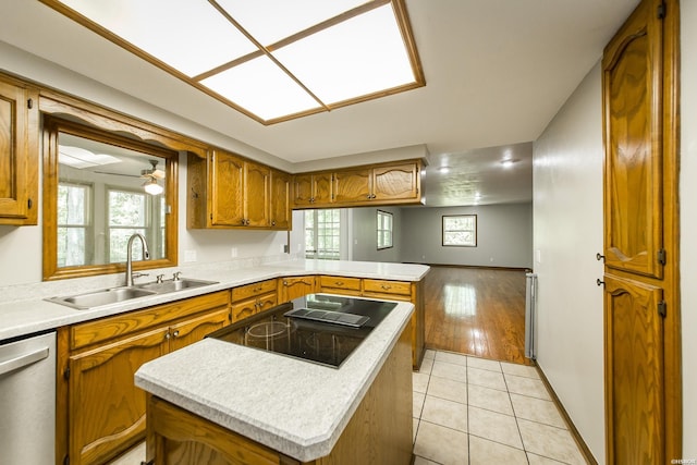 kitchen featuring a kitchen island, brown cabinets, a sink, light countertops, and a peninsula