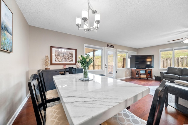 dining space featuring a textured ceiling, baseboards, dark wood finished floors, and a wealth of natural light