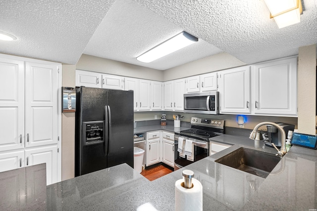 kitchen featuring a textured ceiling, stainless steel appliances, a sink, and white cabinetry