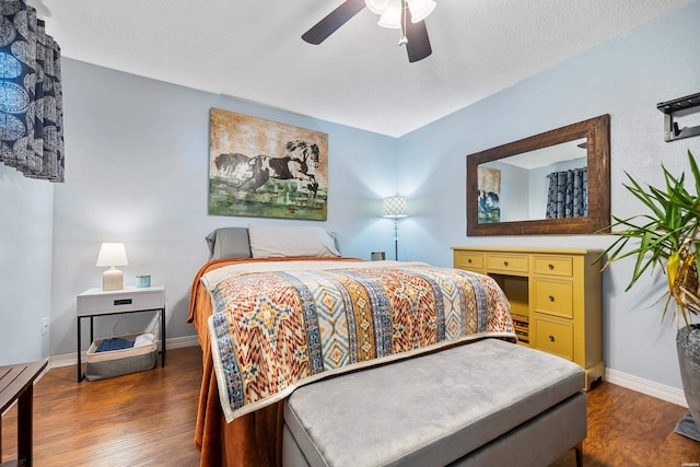 bedroom with a ceiling fan, a textured ceiling, baseboards, and dark wood-type flooring