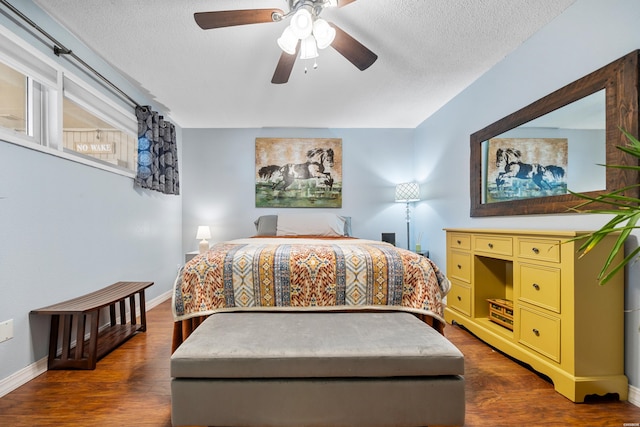 bedroom featuring dark wood-style floors, a textured ceiling, a ceiling fan, and baseboards