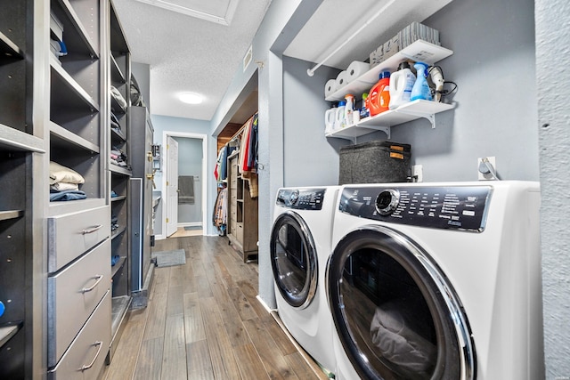 laundry room with a textured ceiling, laundry area, wood finished floors, and washing machine and dryer