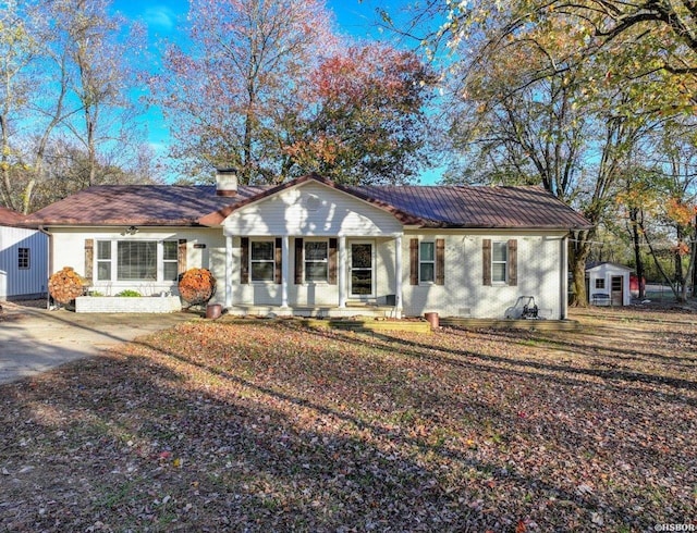 view of front of home with an outbuilding, brick siding, a chimney, a porch, and crawl space