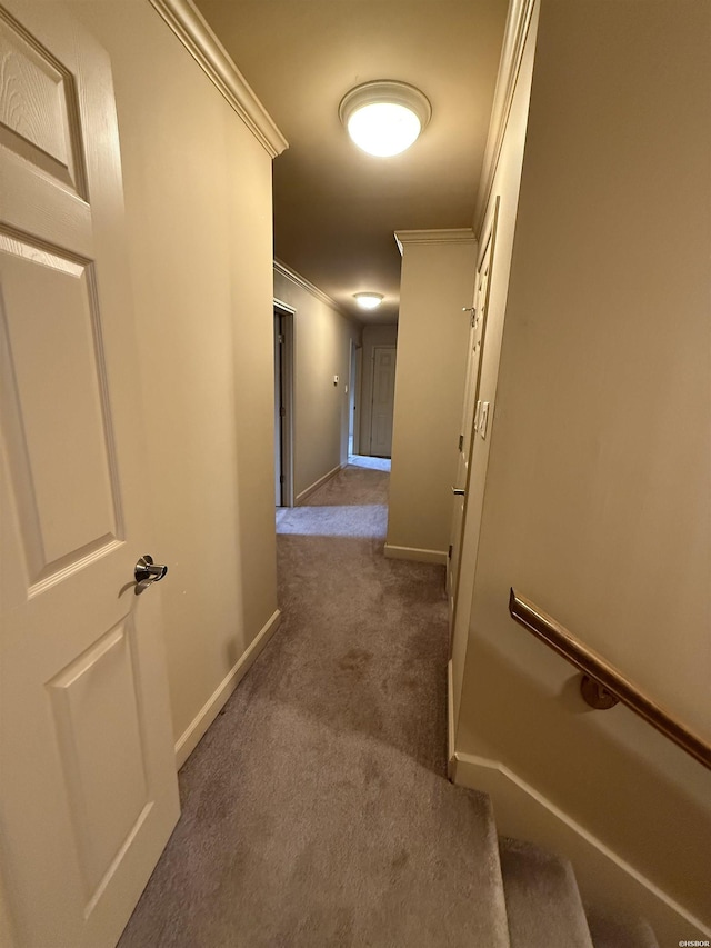 hallway featuring ornamental molding, dark carpet, and baseboards