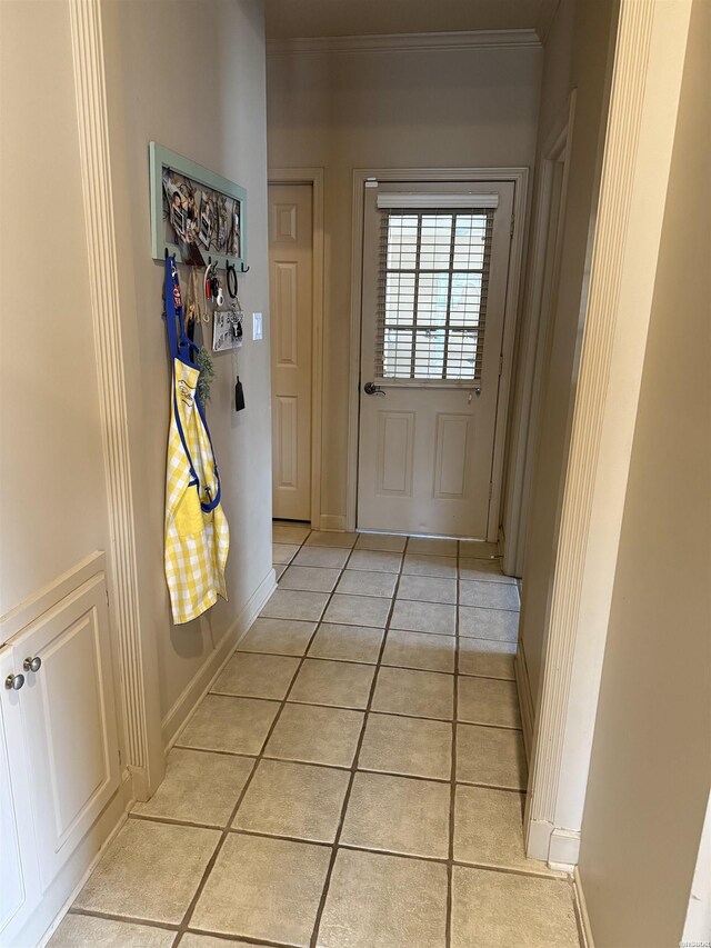 doorway to outside featuring crown molding, baseboards, and light tile patterned floors