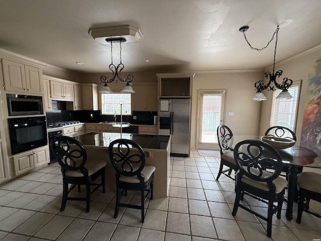 kitchen featuring dark countertops, a kitchen island, hanging light fixtures, and black appliances