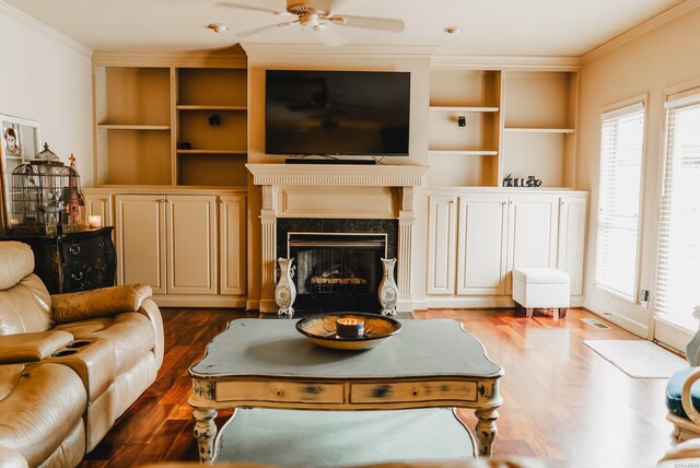 living area with dark wood-style floors, plenty of natural light, a fireplace, and crown molding