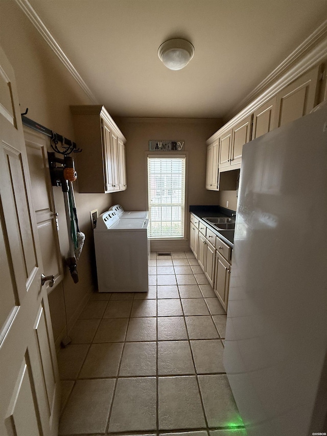 kitchen with cream cabinets, freestanding refrigerator, washer and clothes dryer, dark countertops, and crown molding