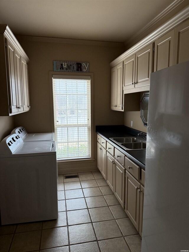 kitchen with a sink, visible vents, freestanding refrigerator, washer and clothes dryer, and dark countertops