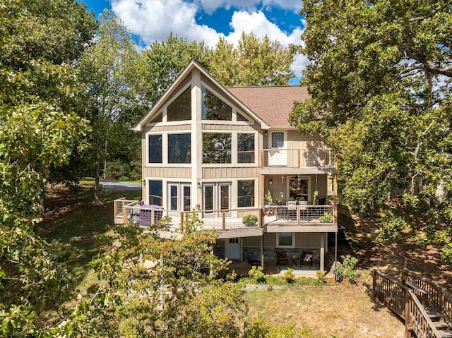 back of property with board and batten siding, stone siding, a patio area, and a balcony