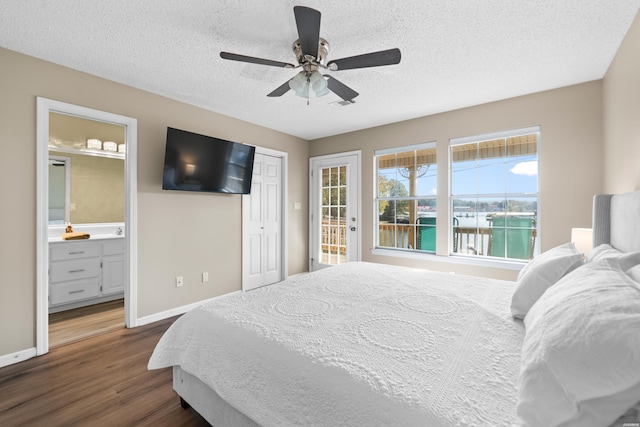 bedroom with dark wood finished floors, a textured ceiling, baseboards, and ensuite bathroom