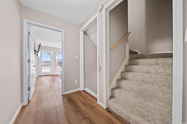 staircase with baseboards and wood finished floors