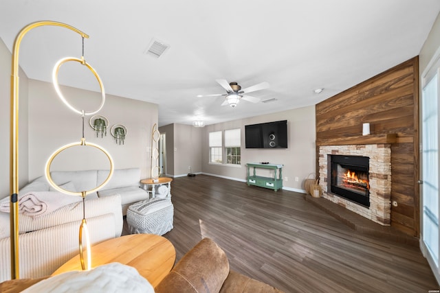 living room with a fireplace, a ceiling fan, visible vents, baseboards, and dark wood-style floors