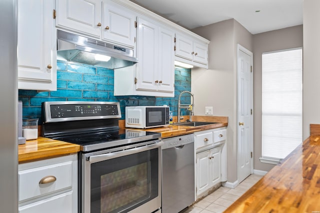 kitchen with under cabinet range hood, a sink, wood counters, white cabinetry, and appliances with stainless steel finishes