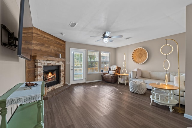 living area with ceiling fan, a fireplace, visible vents, and dark wood-type flooring