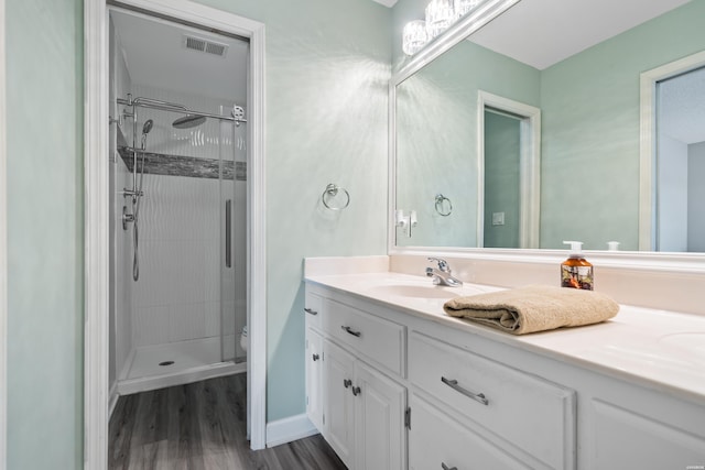 full bathroom featuring toilet, wood finished floors, visible vents, vanity, and a stall shower