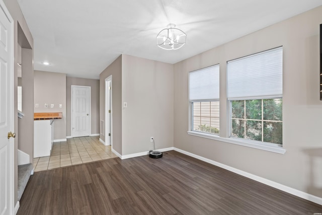 unfurnished room featuring light wood-style floors, baseboards, and an inviting chandelier