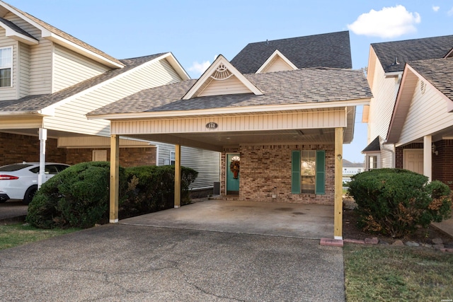 view of front of house featuring a carport, driveway, brick siding, and a shingled roof