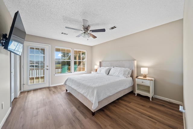 bedroom with baseboards, access to outside, visible vents, and wood finished floors