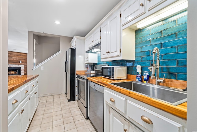 kitchen with white cabinets, butcher block counters, stainless steel appliances, and a sink