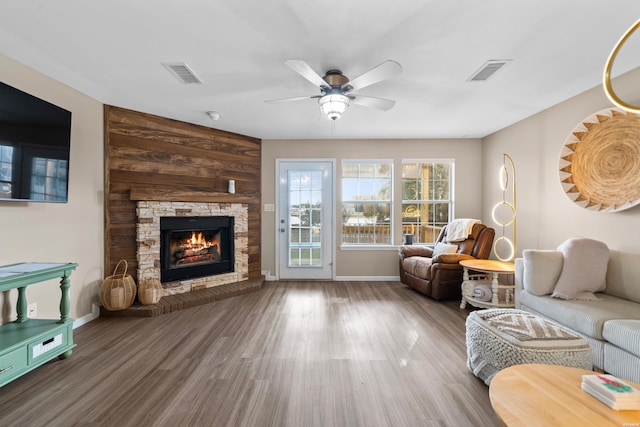 living area with ceiling fan, a fireplace, wood finished floors, and visible vents