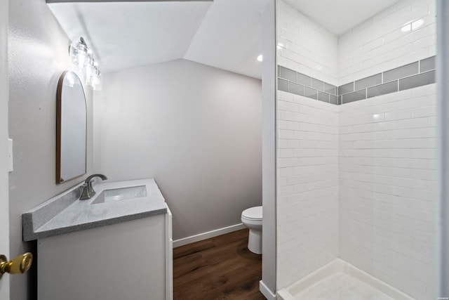 bathroom featuring toilet, wood finished floors, vaulted ceiling, vanity, and a shower stall