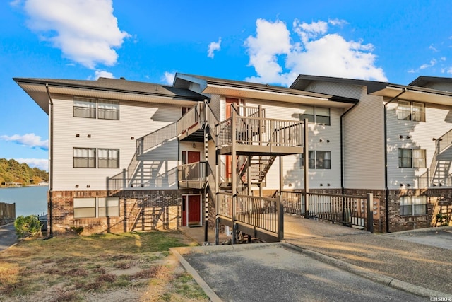 back of property featuring stairs, fence, and brick siding