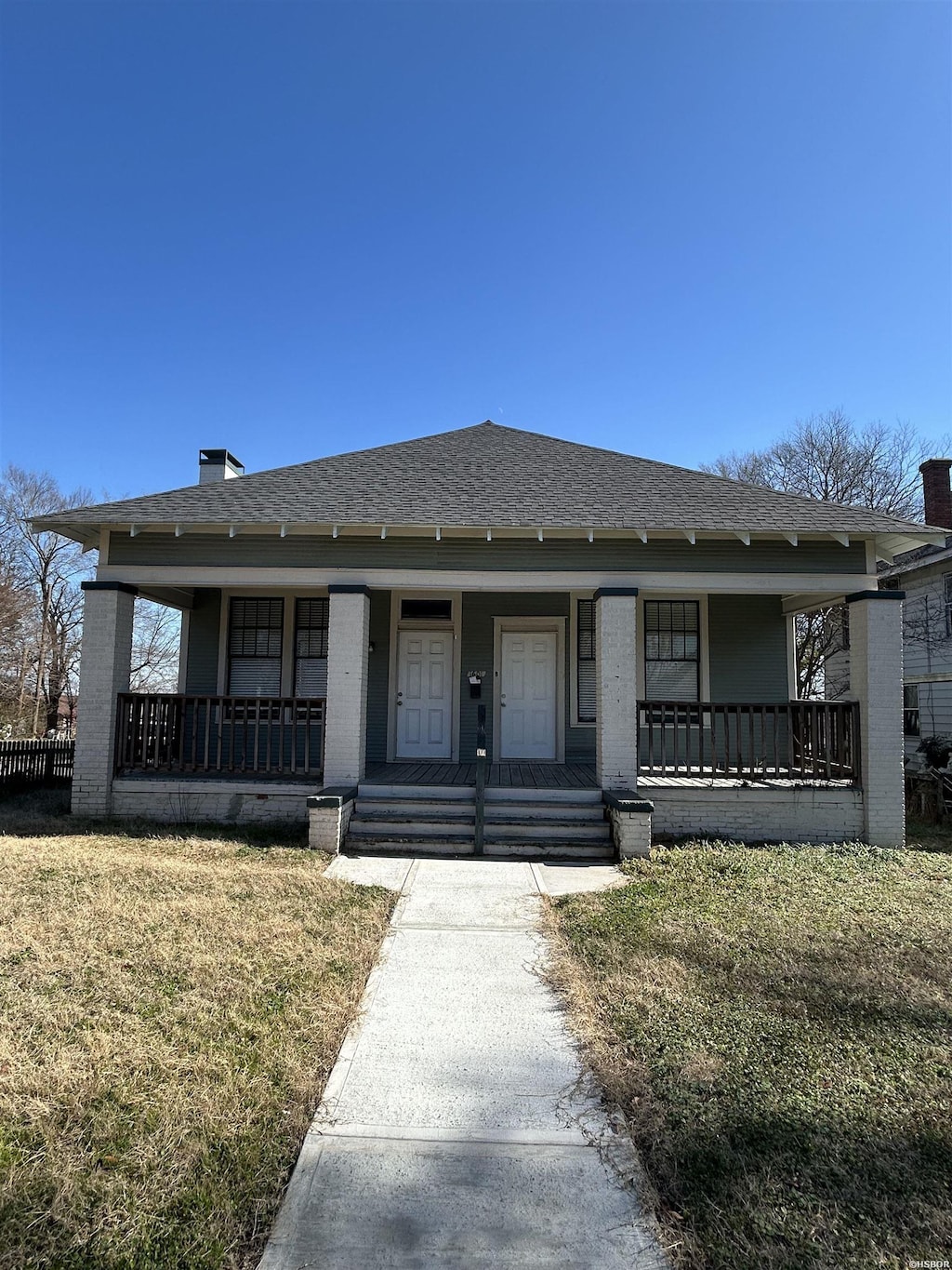 bungalow featuring a shingled roof, a front yard, a porch, and brick siding