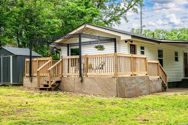 back of house with a lawn, stairway, a wooden deck, and an outbuilding