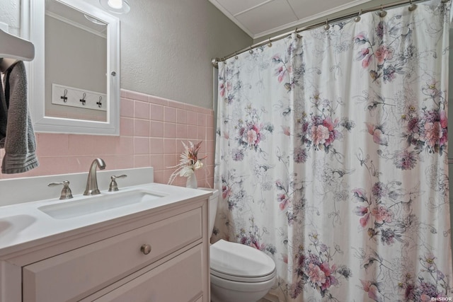 bathroom with curtained shower, toilet, tile walls, vanity, and wainscoting