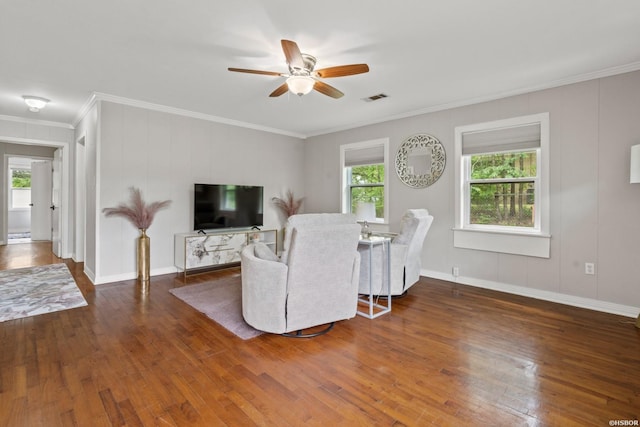 living area with wood finished floors, ornamental molding, ceiling fan, baseboards, and visible vents