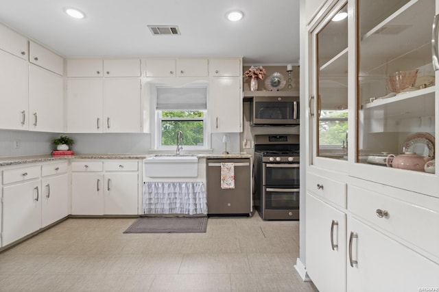 kitchen with a sink, stainless steel appliances, visible vents, white cabinetry, and light countertops