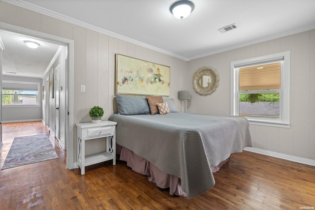 bedroom featuring baseboards, visible vents, ornamental molding, and wood finished floors