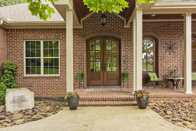 entrance to property with brick siding, a shingled roof, and french doors