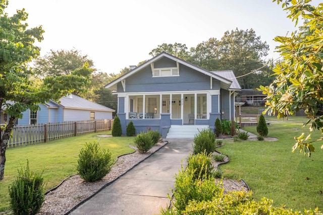 bungalow-style home with metal roof, a porch, a front yard, and fence