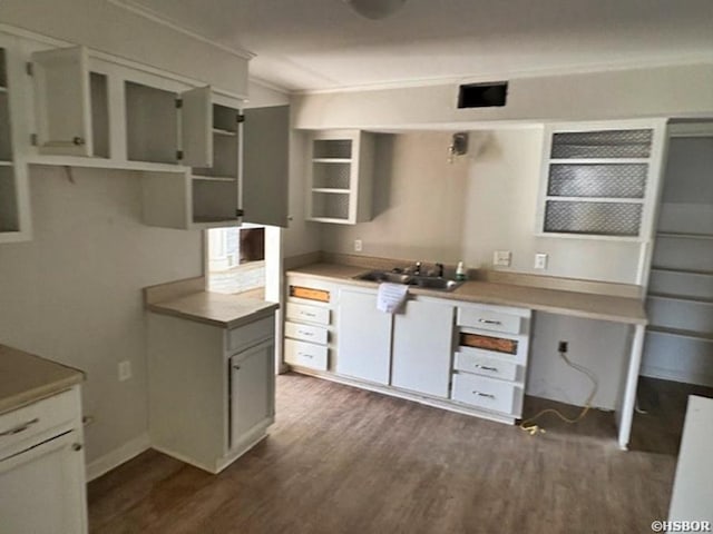 kitchen with dark wood-style flooring, crown molding, open shelves, light countertops, and a sink