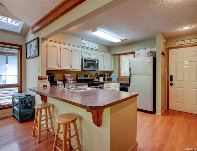 8 Redbird Ln Unit D, Mount Ida, AR 71957 - kitchen with appliances with stainless steel finishes, a textured ceiling, a peninsula, a sink, and light wood finished floors