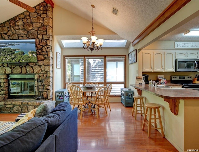 8 Redbird Ln Unit D, Mount Ida, AR 71957 - kitchen featuring appliances with stainless steel finishes, a sink, a breakfast bar, white cabinetry, and a chandelier