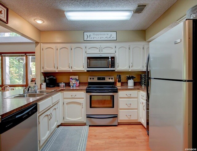8 Redbird Ln Unit D, Mount Ida, AR 71957 - kitchen featuring appliances with stainless steel finishes, a sink, a textured ceiling, light wood-style flooring, and white cabinetry