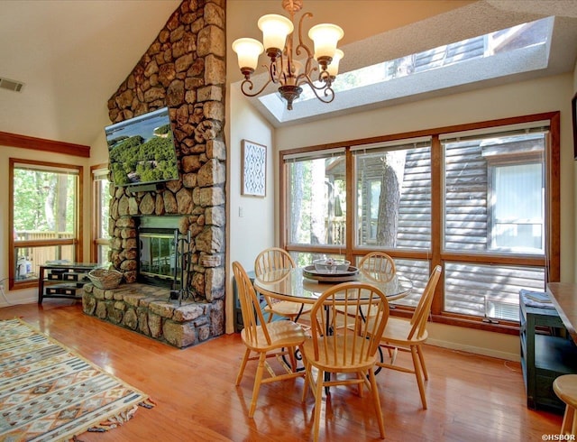 8 Redbird Ln Unit D, Mount Ida, AR 71957 - dining space with wood finished floors, a stone fireplace, a chandelier, high vaulted ceiling, and baseboards